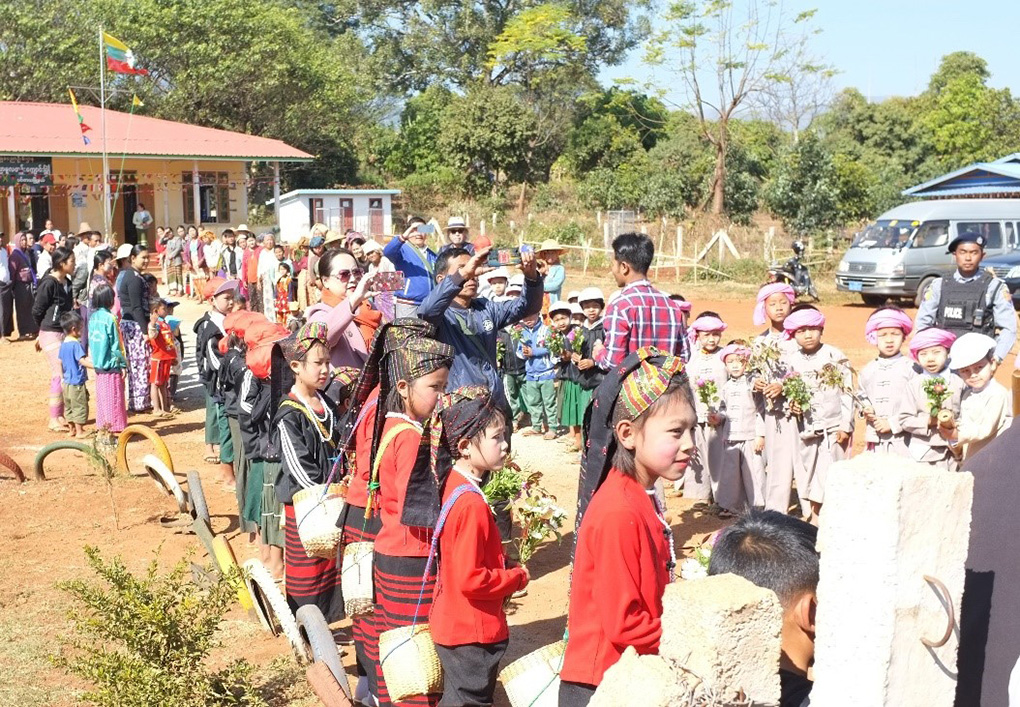 写真：植樹祭を歓迎する子供たち（後方の建物：寄付先の小学校）